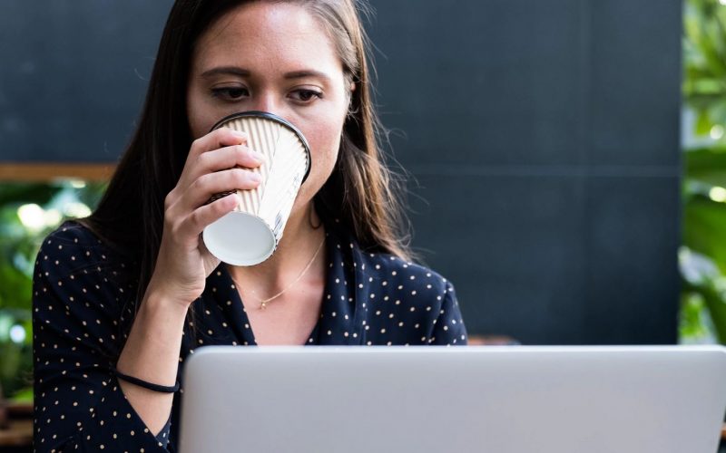 Woman drinking coffee browsing laptop